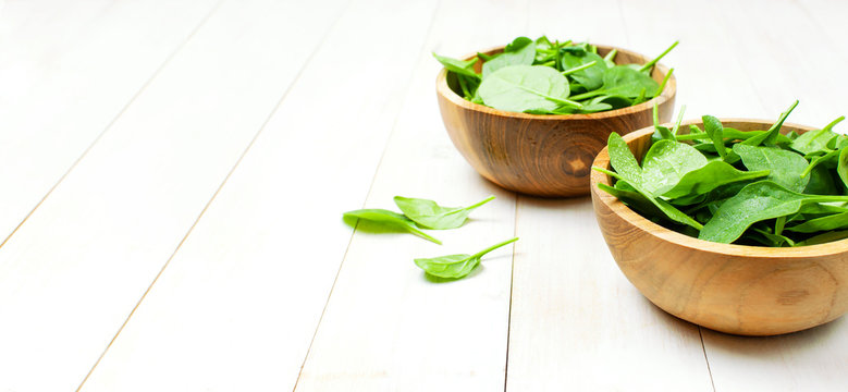 Fresh green spinach leaves on wooden bowl on white wooden rustic background Selective focus copy space. Baby young spinach leaves, Ingredient for salad, healthy food, diet. Nutrition concept.