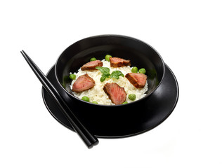Rice with meat pieces, basil and green peas in a plate on a white background. 
