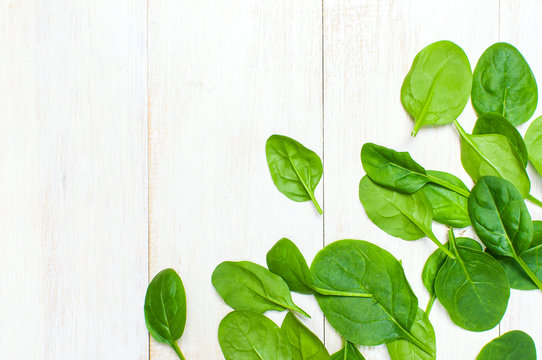 Fresh green spinach leaves on white wooden rustic background top view copy space. Baby young spinach leaves, Ingredient for salad, healthy food, diet. Nutrition concept.