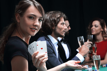 Portrait of the female gambler at the poker table with cards