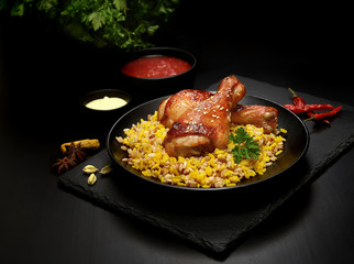 grilled chicken legs with sesame and rice on a black background.