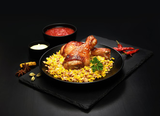 grilled chicken legs with sesame and rice on a black background.