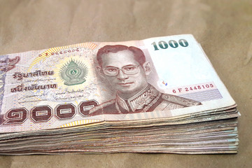 A lot of 1,000 Baht Thailand banknote placed on brown paper