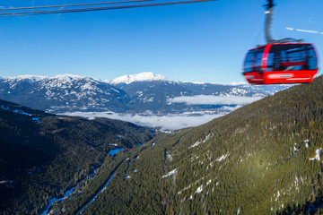 A large gondola car streaking by with the valley in between Whistler and Blackcomb in the background. © Adam