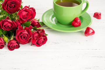 Valentine's day background with tea cup, sweets and red roses.