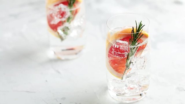 Alcoholic cocktail with grapefruit, soda, ice, gin and rosemary, light gray concrete table background, selective focus, shallow depth of the field.