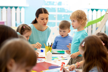 Kindergartener teaches children handcraft at nursery or playschool