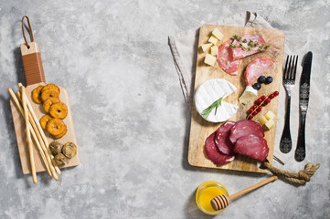 Italian antipasto with prosciutto, salami, Parmesan, brie and Gorgonzola cheese, honey, top view, grey background