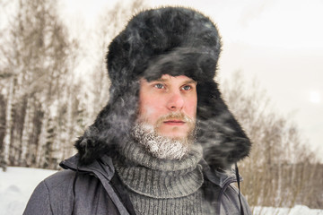 frozen man with a beard in winter in a forest with snowdrifts fell ill from the cold after a walk in the village