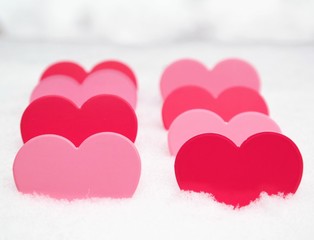 valentines day concept with paper shaped hearts in pink colors. beautiful multiple hearts in real snow. winter greeting card with copy space