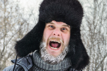 frozen sick grandfather in the woods in a hat with earflaps in the village in the cold screaming...