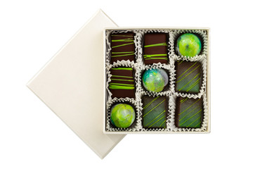 Assortment of luxury bonbons with green splashes in white box isolated on white background