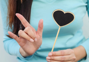 Closeup wooden black board in heart shape with finger of woman in love mean