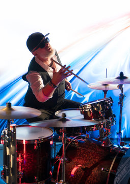 Emotional drummer playing on drum set on stage in the color light 