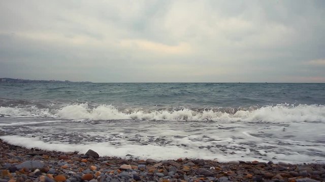 Abstract landscape. Sea waves run to the beach. Multi-colored stones and sand. Slow motion.