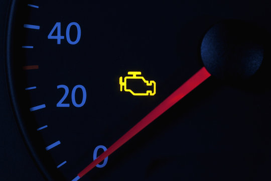 yellow engine check engine icon on car dashboard, black background