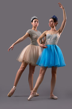 Two ballerinas posing and dancing together in studio