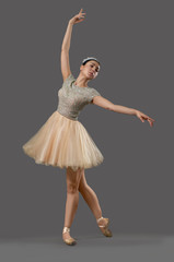 Naklejka premium Ballerina in beige dress and ballet shoes dancing in studio