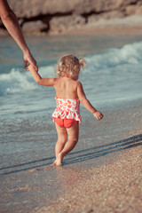 pretty girl goes by the hand with her father along the shore of the sea