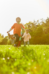 Kinder laufen ausgelassen auf einer Wiese