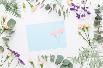 Flowers composition. Paper blank, carnation flowers, eucalyptus branches on pastel  background. Flat lay, top view, copy spaceFlat lay stiil life.