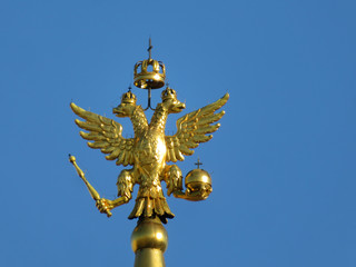 Fototapeta na wymiar Double-headed eagle, symbol of Russia isolated on blue sky background. Golden russian emblem on the top of tower on Red square in Moscow