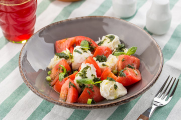 Caprese salad with mozzarella, tomato, basil and balsamic vinegar served on the table
