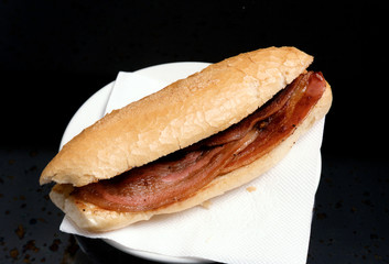 Bocadillo con una barrita de pan tostado y unas lonjas de beicon.