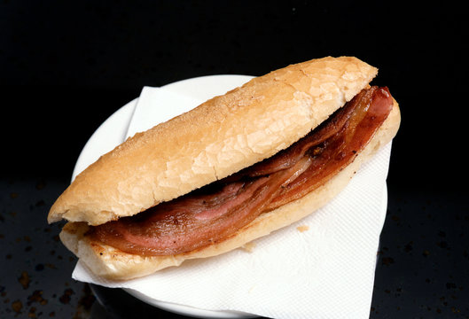 Bocadillo con una barrita de pan tostado y unas lonjas de beicon.