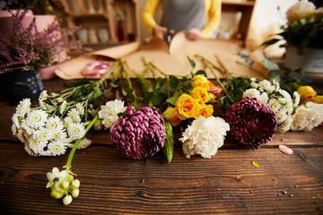Close up of beautiful flowers lying on wooden table in flower shop, copy space