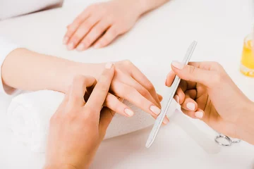  Gedeeltelijke weergave van manicure die vingers vasthoudt terwijl hij nagelvorm doet © LIGHTFIELD STUDIOS