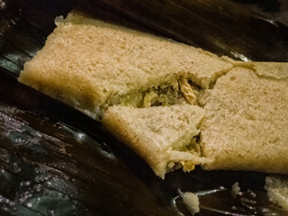A Oaxacan style mexican tamale broken open to display chicken filling, cooked in banana leaf. Mexican food, travel in Mexico.