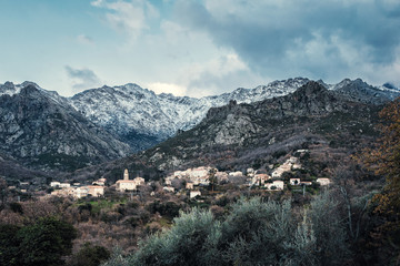 Fototapeta na wymiar Feliceto village and snow covered mountains in Corsica