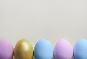 A row of pastel colored Easter eggs on white background. Festive easter background in minimalism style.
