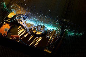 closeup on open hard disk with colored fiber optics, tech background.