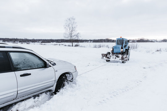 Tractor towing car on snow field