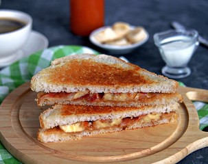Sandwiches with peanut butter, banana and fried bacon on a wooden board.