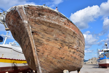  Lavoro di rimessaggio su barca da pesca in legno. La vernice della barca viene tolta dalla carena...