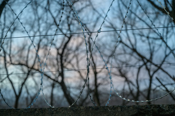 Barbed wire on fence with sky. Selective focus.