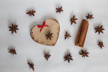 Star anise, cinnamon sticks and wood heart on a white background.