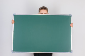 Frightened boy holding a message board, hiding behind her so that only his eyes and the tips of his ears are visible