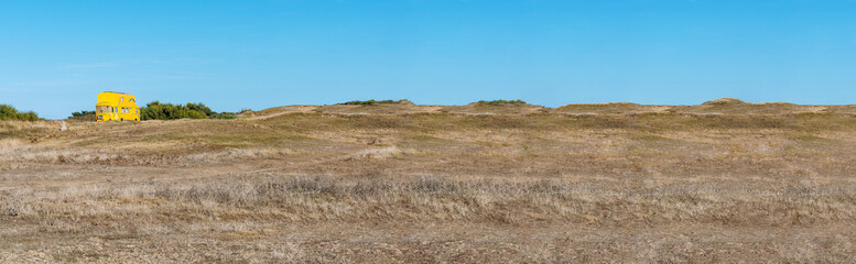 French landscape - Bretagne. Yellow double-decker bus in dunes at a sunny day.