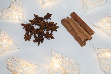 Star anise, cinnamon sticks and white hearts on a white background.