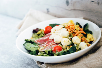 Salad with fusilli pasta accompanied tomatoes, mozzarella, smoked ham and italian cheese