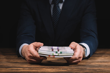 mid section of businessman holding russian rubles banknotes above wooden table