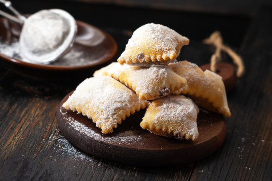 Ravioli filled with chocolate , carnival italianfritters on dark rustic board.