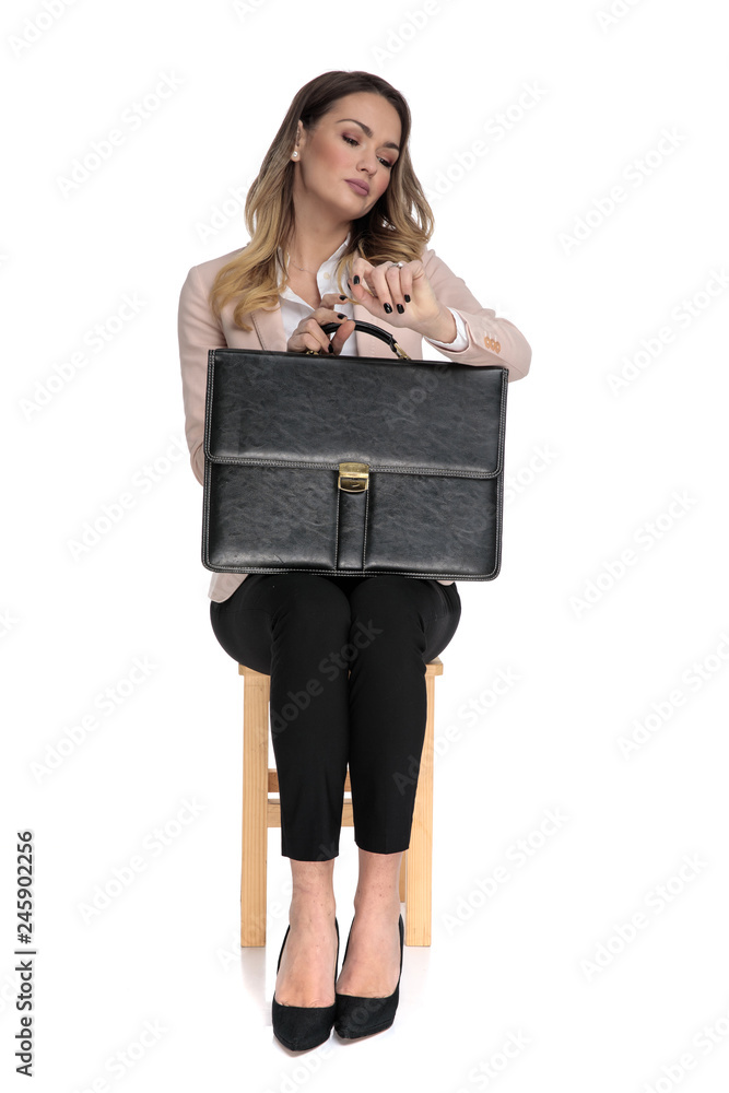 Sticker impatient businesswoman sits while holding briefcase and looking at watch