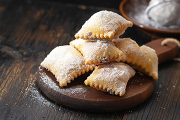 Ravioli filled with chocolate , carnival italianfritters on dark rustic board.