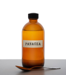 Panacea, magic potion. Old brown glass medicine bottle with spoon, label. Pharmaceutical concept or ironic metaphor, wishful thinking. White behind.