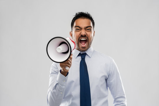 Business, Stress And People Concept - Indian Businessman Screaming To Loudspeaker Over Grey Background